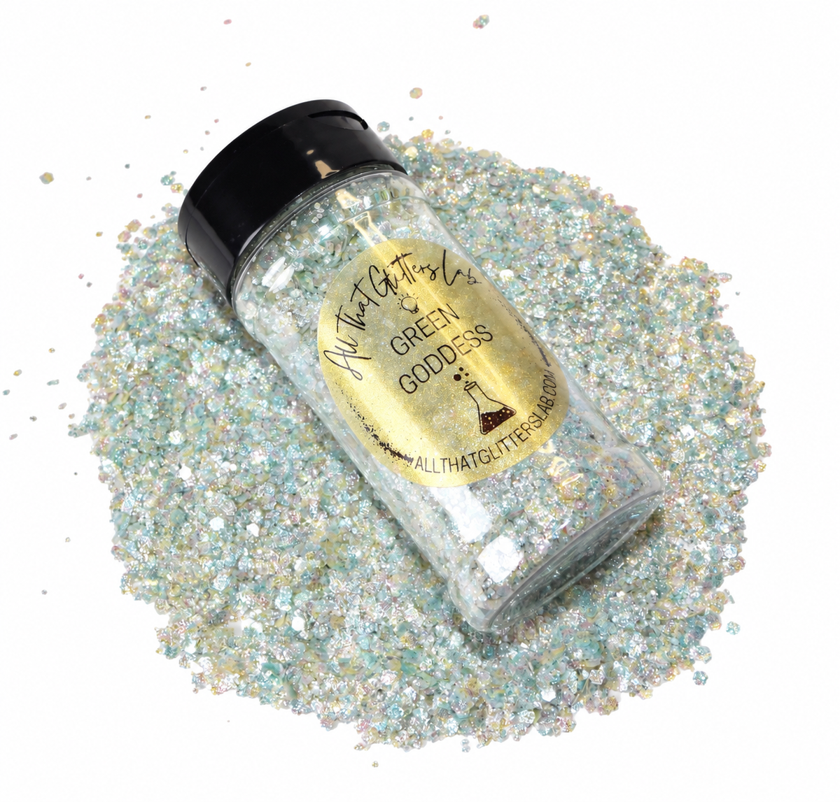 A clear plastic jar of All That Glitters 'Green Goddess' glitter with a black lid and gold label, surrounded by spilled iridescent light green, silver, and gold glitter on a white background.