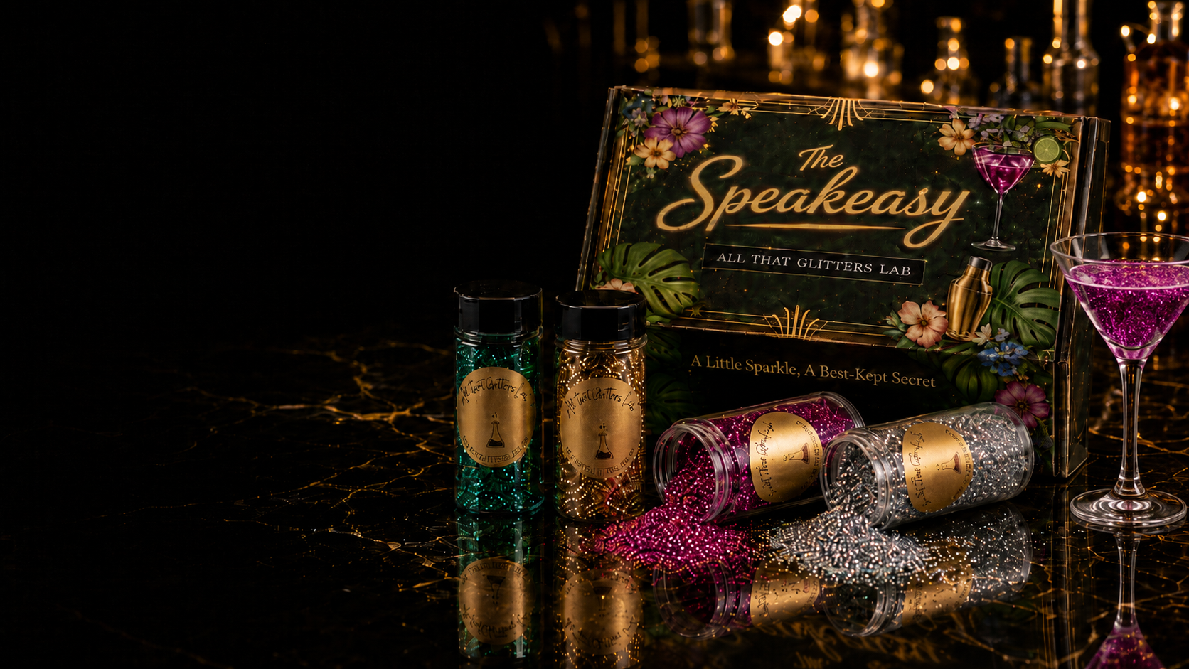The Speakeasy sign by All That Glitters Lab surrounded by jars of pink, gold, teal and silver glitter and a pink glitter martini